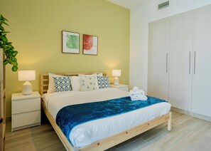 A neatly arranged bedroom with a bed, bedside tables, a wardrobe, and two wall-mounted artworks. - Maison Privee - Modern Yas Island Escape w/ Peaceful Canal Views (Abu Dhabi)