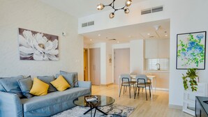 A modern living room with a grey sofa, a glass coffee table, and a blue patterned rug. - Maison Privee - Modern Yas Island Escape w/ Peaceful Canal Views (Abu Dhabi)