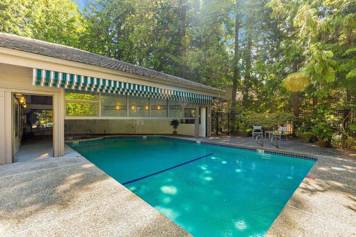 A swimming pool with a covered area, surrounded by trees.