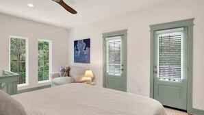 A bedroom with a bed, a ceiling fan, a nightstand with a lamp, and two doors with window blinds. - "Idlehour" new cottage in Fairhope, AL - NEW LISTING (Fairhope)