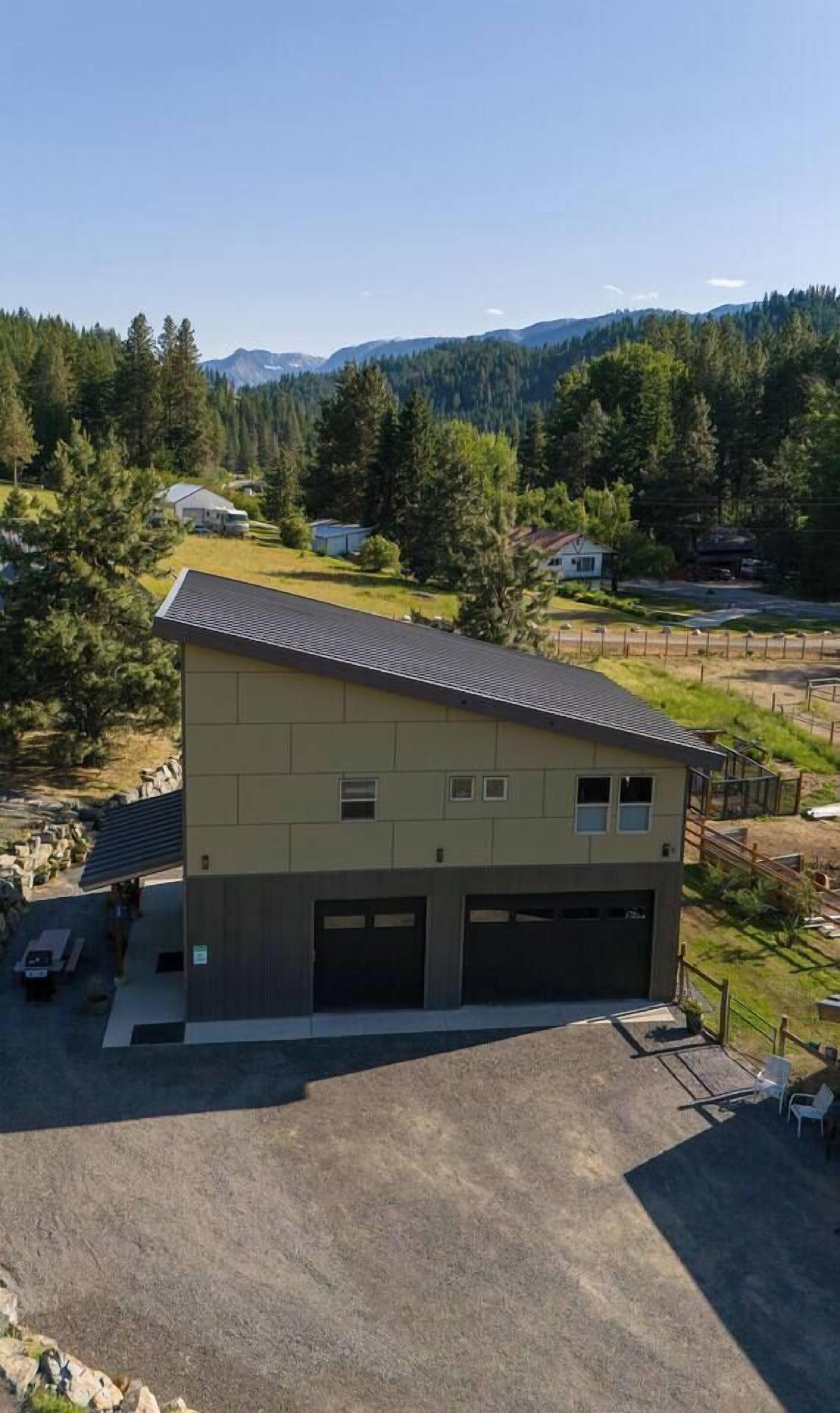 Ein modernes, zweistöckiges Gebäude mit Flachdach und Garage. Es ist von einer Umzäunung mit einem Schotterweg umgeben.