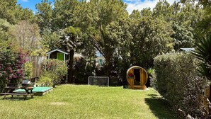 Patio con un barril de madera, una mesa verde y una portería de fútbol.