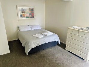 Cozy retreat with a comfortable bed, dresser, and framed village view.