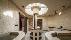 A modern spa with two large tubs, a central column, and a skylight.