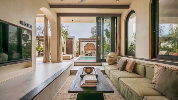 A modern living room with a sofa, a coffee table, and a view of an outdoor pool area.