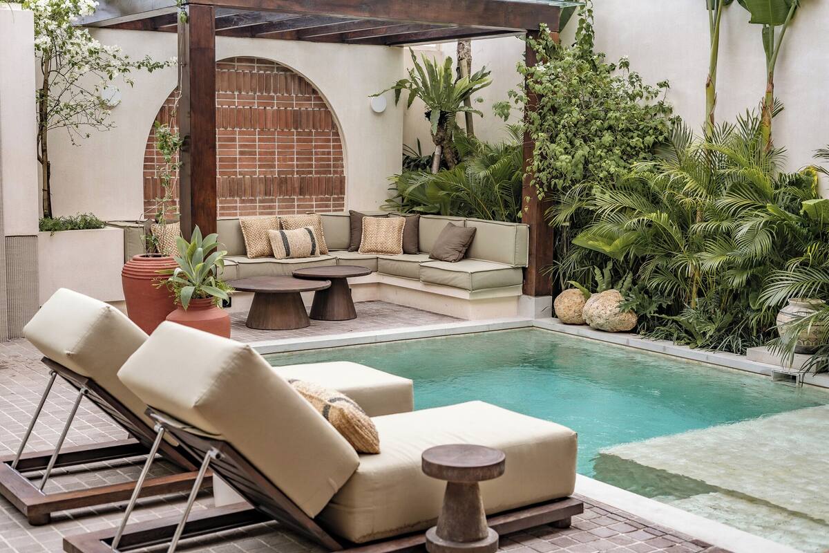 Un espace aménagé au bord de la piscine, avec un canapé, des chaises longues et une petite table.