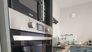 A modern kitchen with a built-in oven, a microwave, and a stainless steel range hood. - Gîte du Clos du Parc, in the heart of the farm (CHINON)