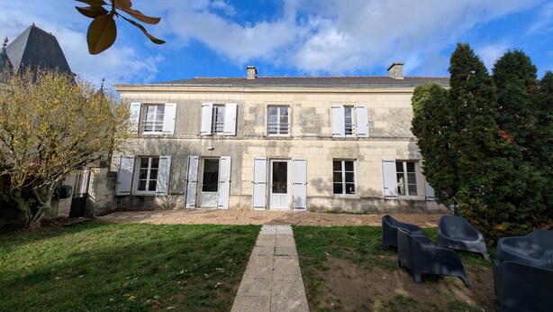 A two-story stone building with white shutters, a paved courtyard, and outdoor seating. - Gîte du Clos du Parc, in the heart of the farm (CHINON)