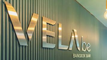 A metallic sign with the text "VELA" and "BANGKOK SIAM" against a corrugated metal background.