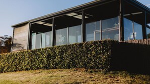 A modern building with large windows and a covered outdoor area. - A Romantic Escape in Nature’s Embrace (Bullarto South)