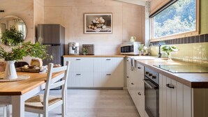 A modern kitchen with white cabinetry, a wooden countertop, and a large window. - A Romantic Escape in Nature’s Embrace (Bullarto South)