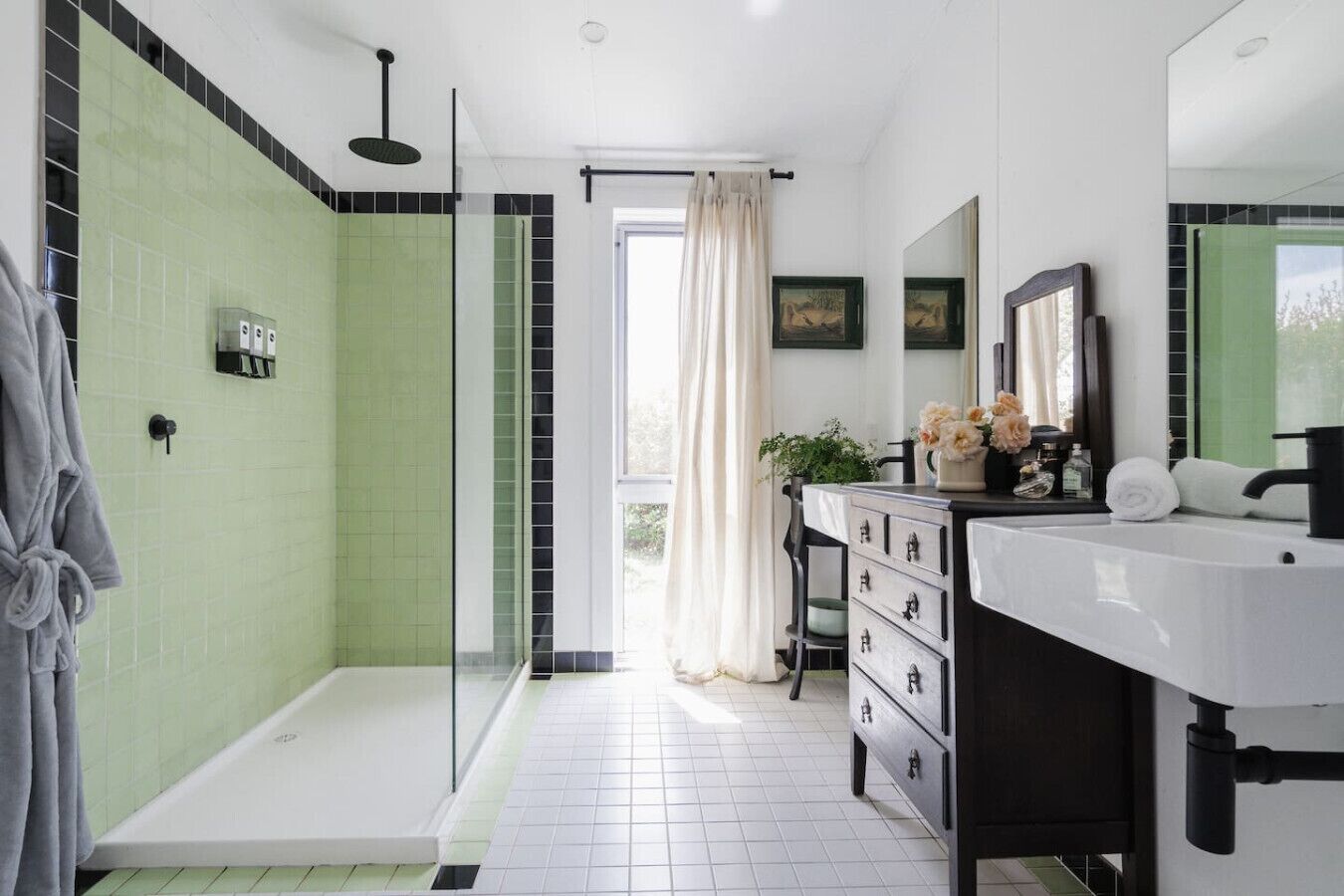 A modern bathroom with a shower, a vanity with a mirror, and a window with a view.