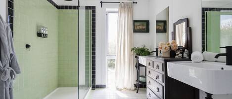 A modern bathroom with a shower, a vanity with a mirror, and a window with a view.
