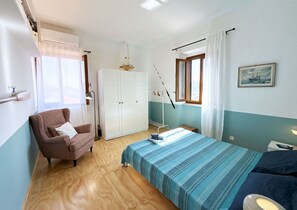 A bedroom with a bed, a chair, a wardrobe, and a window with curtains. - Angoli del Mare, a corner of paradise! (Portoferraio)