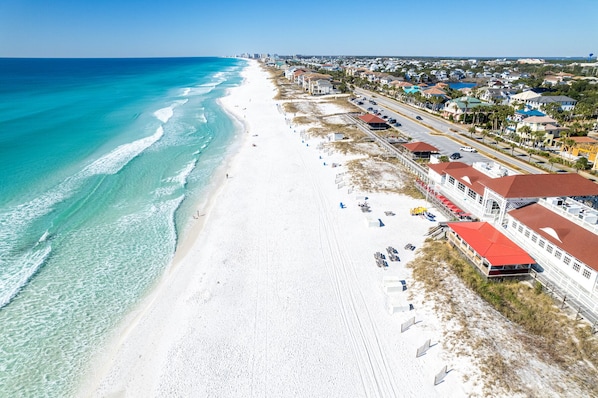 A coastal beach with a row of beachfront buildings, clear turquoise waters, and a wide sandy beach.