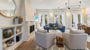 Ein modernes Wohnzimmer mit Kamin, einem blauen Sofa und einer Chandelier.