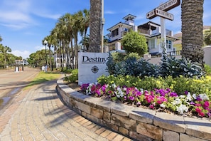 A sign for 'Destiny' hotel with a paved pathway, palm trees, and a building with balconies.