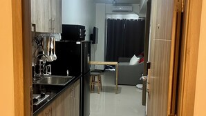 Una cocina compacta con refrigerador, estufa y lavamanos. Hay un comedor con una mesa y sillas.