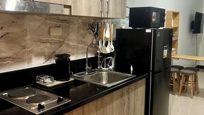 A modern kitchen with wooden cabinets, a black refrigerator, a stove, and a sink.