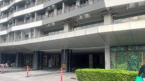 Entrada de un hotel de varios pisos con un corredor cubierto, una rampa accesible para sillas de ruedas y un dispositivo de seguridad.