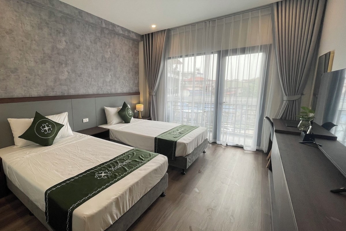 Ein Hotelzimmer mit zwei Betten, einem Schreibtisch und Blick ins Freie.