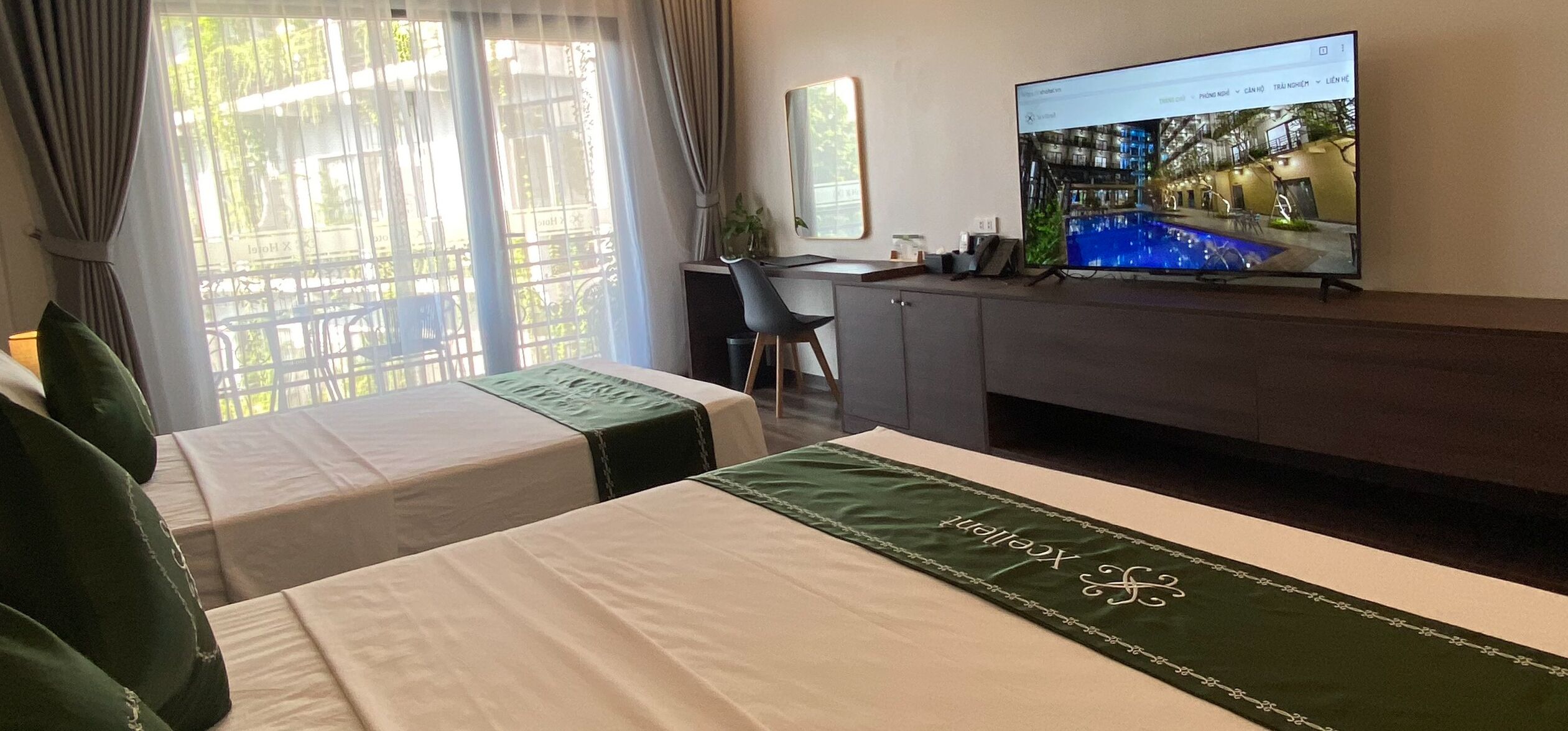 Une chambre d’hôtel avec deux lits, un bureau, une télévision et une fenêtre avec des rideaux.