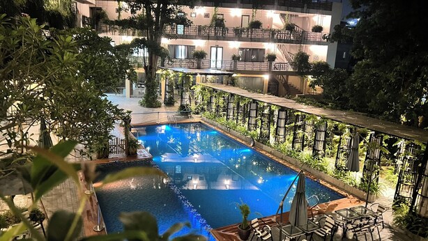 Area piscina con vista aperta sugli edifici circostanti, inclusi balconi con piante.