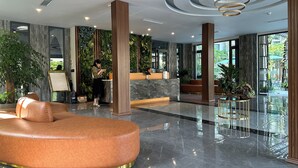 Una hall d'albergo moderna con una reception, un'ampia poltrona in pelle e un tavolino in vetro.