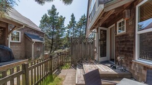 A wooden deck with a patio table and chairs, surrounded by a wooden fence and trees. - SeaEscape: Cute home, dog ok, near beach & pub! (Pacific City)