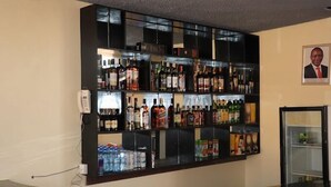 A bar area with shelves stocked with various bottles and cans, a phone on the left, and a framed picture on the wall. - Helsinki Hotel Nyamira (Nyamira)