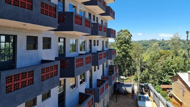 A multi-story building with balconies, large windows, and a view of a green landscape. - Helsinki Hotel Nyamira (Nyamira)