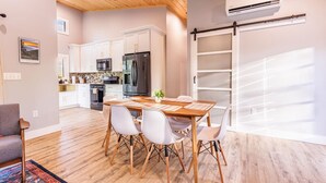 A modern kitchen with white cabinets, a black refrigerator, and a wooden ceiling.