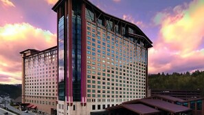 Un hotel de varios pisos con un diseño arquitectónico moderno, que destaca por una fachada de vidrio prominente y un techo curvo.