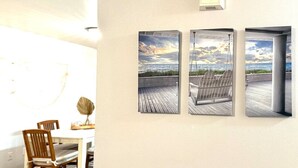 A dining area with a table and chairs, and three framed pictures of a beach scene. - Seaside Escape | Walk to Downtown Meridian • Garage • Pet Friendly • Fenced Yard • Near Roaring Springs & Wahooz (Meridian)