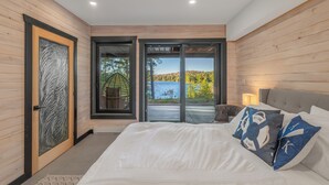 Un dormitorio con una cama grande, vista a un lago y paredes de madera.