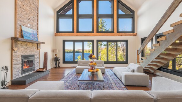 Un salón amplio con chimenea, ventanas grandes y una escalera moderna.