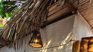 Ein weißes Gebäude mit einem strohgedeckten Dach, einem Holzschild mit der Aufschrift 'MIAMI' und Bambuspfeilern.