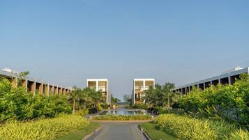A pathway leading to a pool with modern buildings on either side, surrounded by greenery.