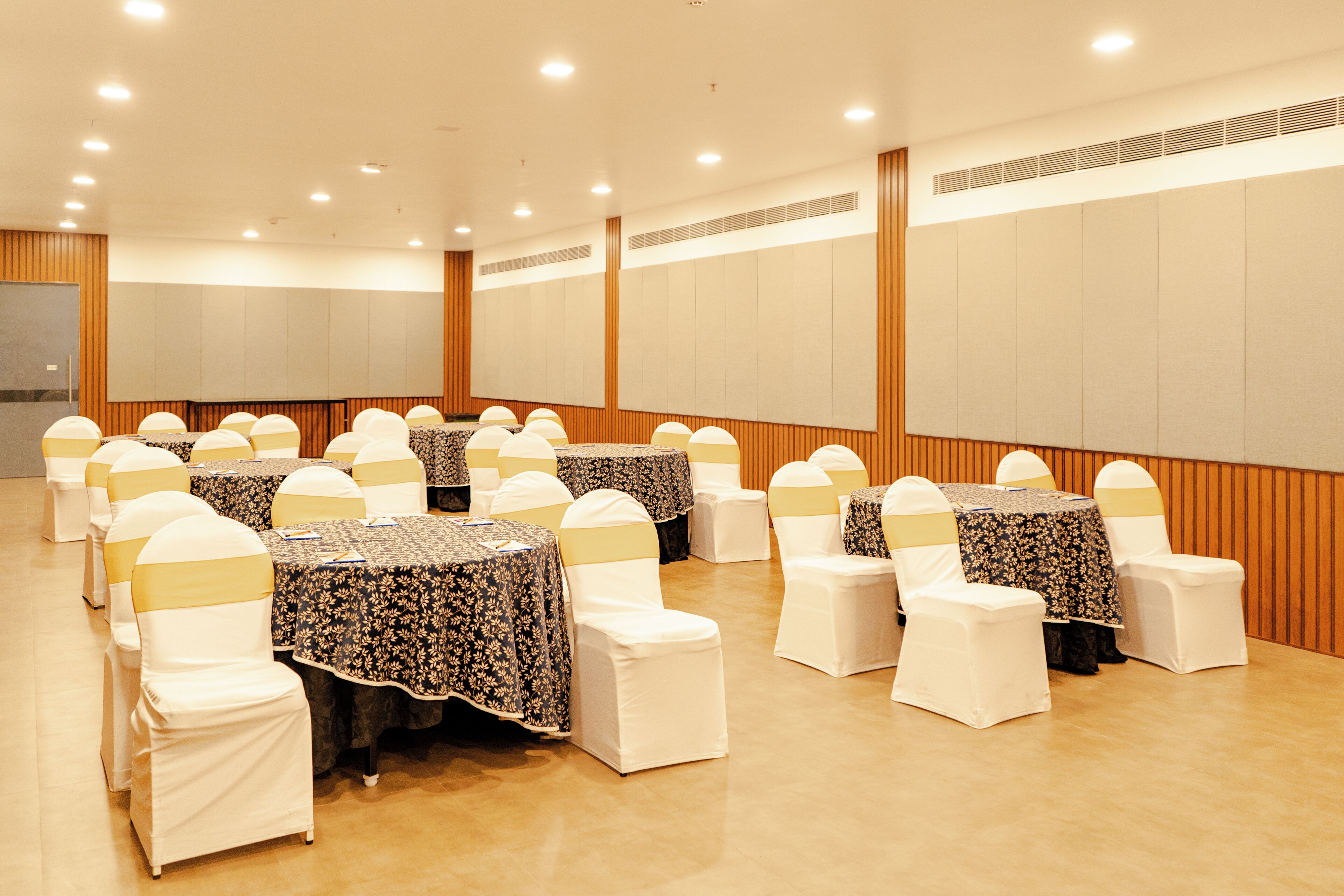 A conference room with round tables, white chairs, and beige accents.