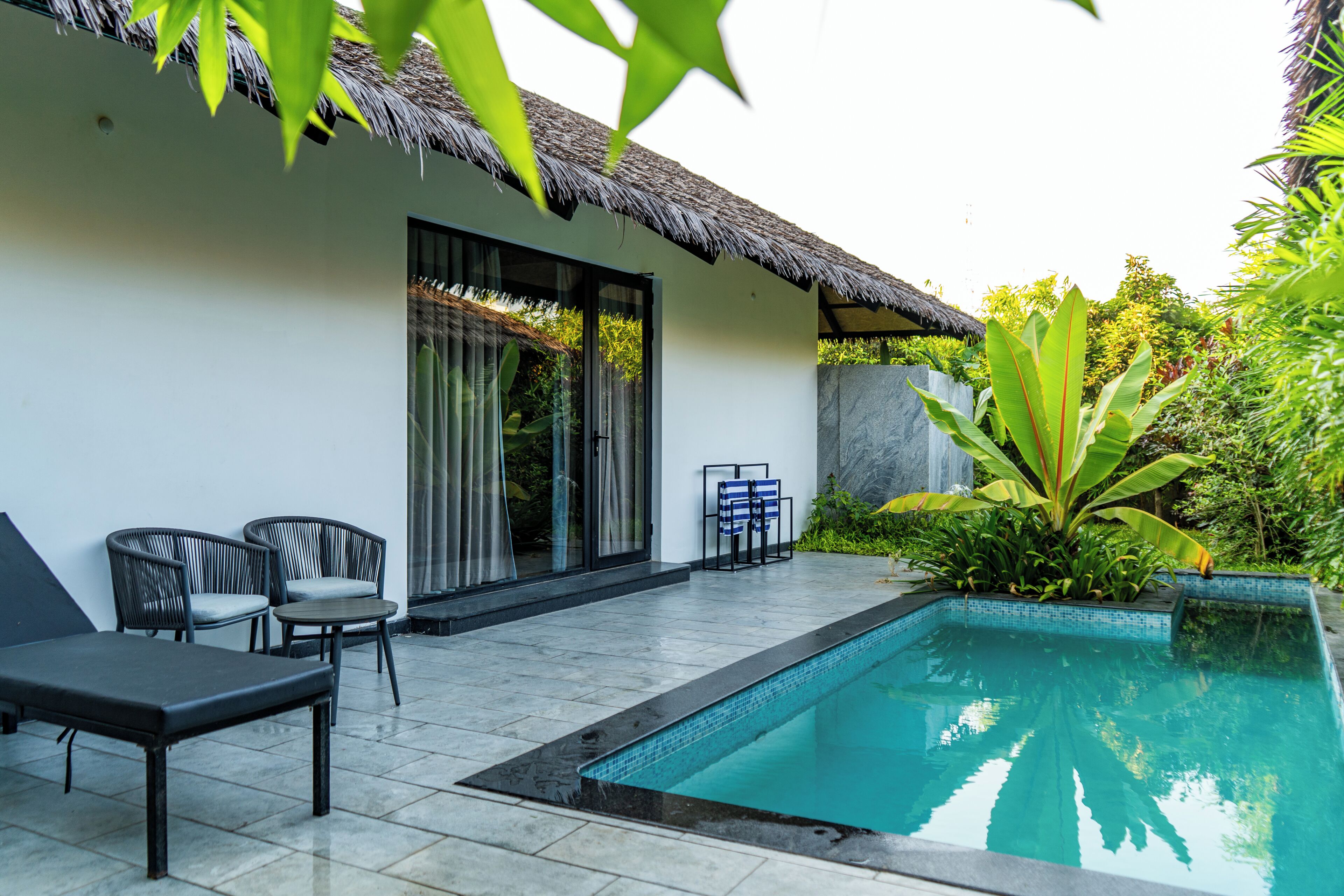 A poolside area with a thatched roof, a pool, and outdoor seating.