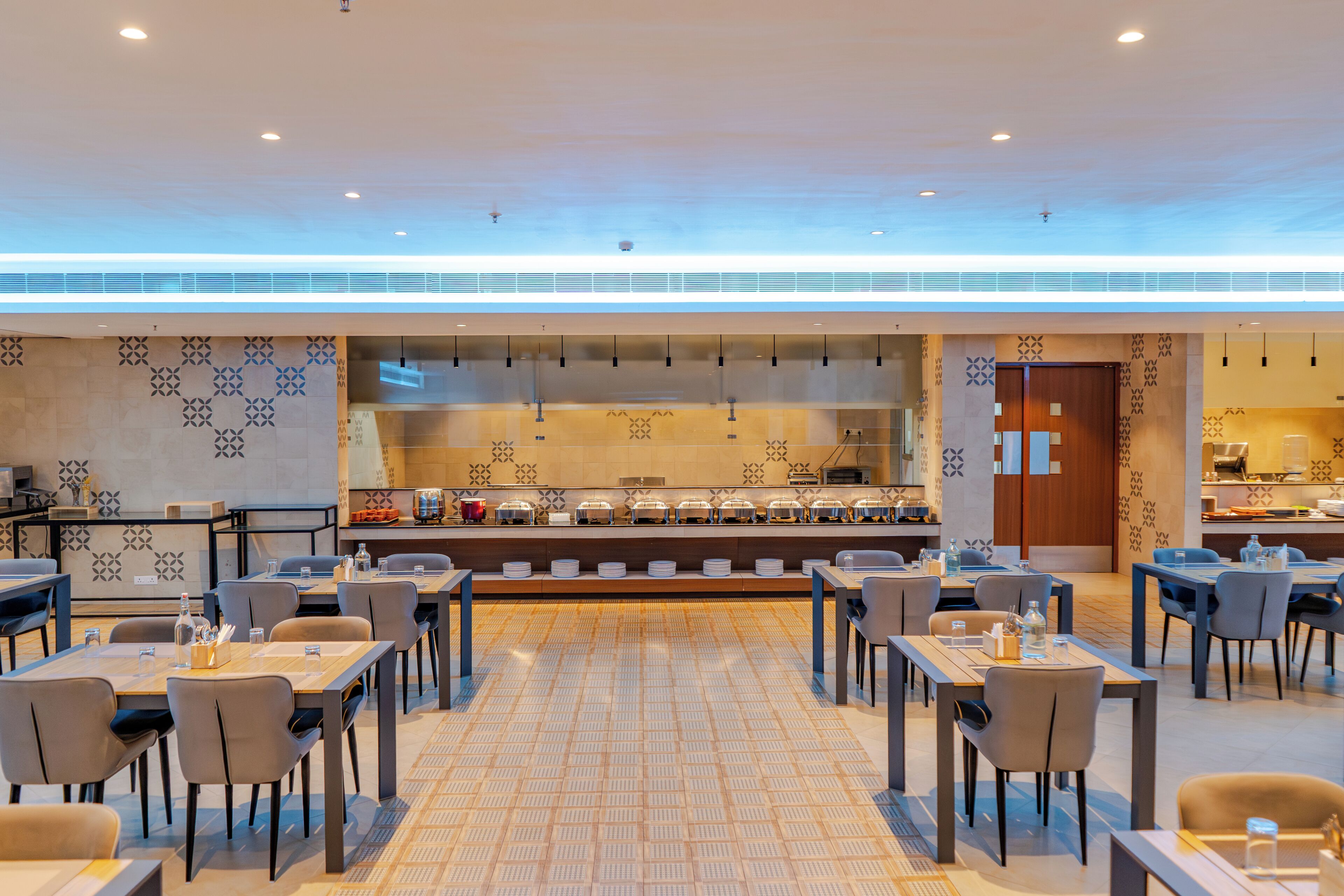 Un comedor moderno con mesas, sillas y una barra de buffet.