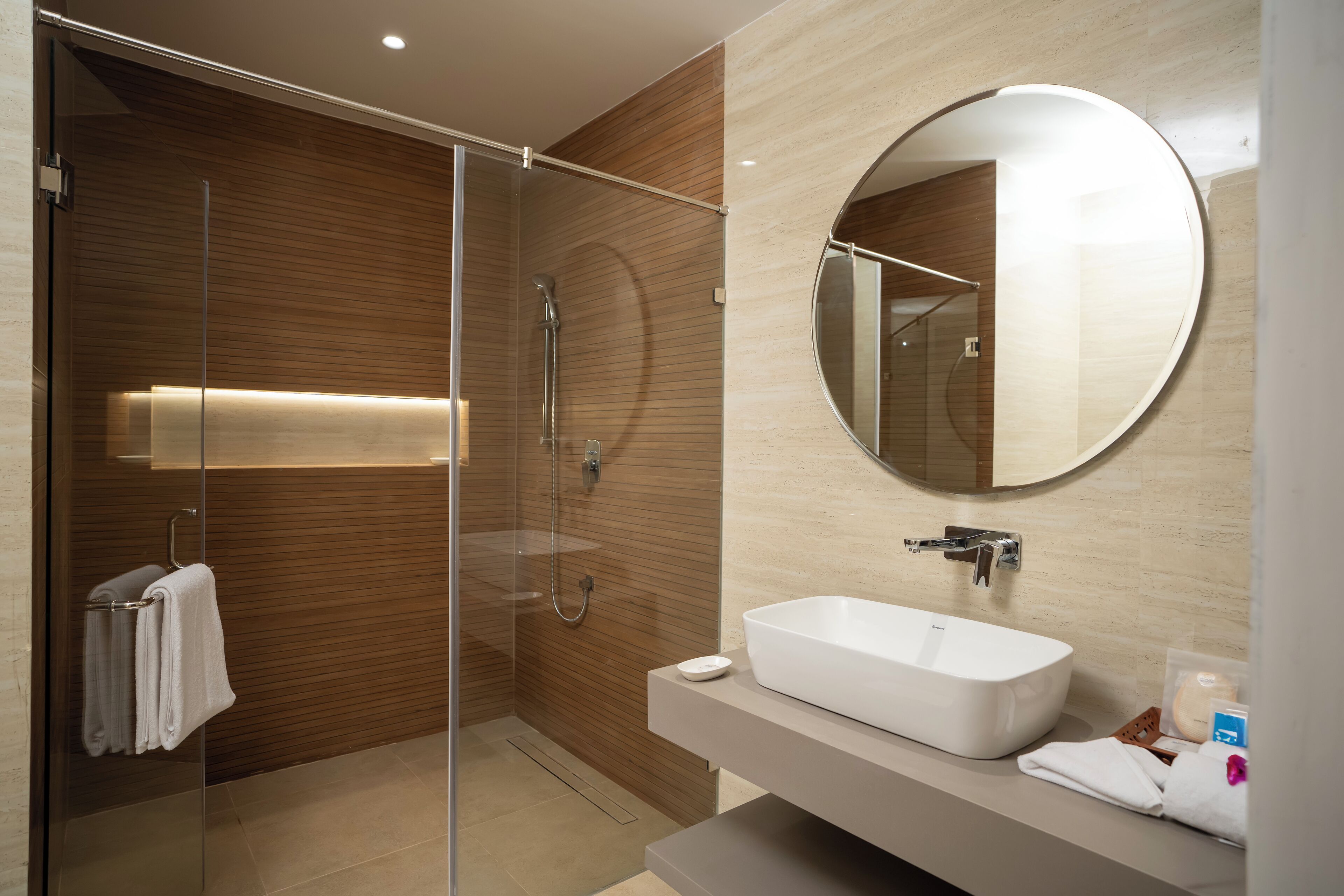 A modern bathroom with a glass-enclosed shower, a white sink, and a large mirror.