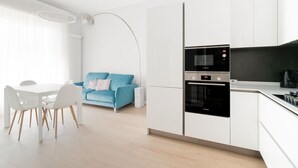A modern kitchen with white cabinetry, a Bosch oven, and a dining area with a white table and chairs. - GuestHost - Bright apartment of about 85 sqm, able to accommodate up to 5 people, located on the mezzanine floor of a building (NO elevator - there are some steps to climb).The property is located in a residential area of ​​Milan, full of services an (Milan)