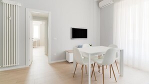 A modern, well-lit room with a white dining table, chairs, and a flat-screen TV mounted on the wall. - GuestHost - Bright apartment of about 85 sqm, able to accommodate up to 5 people, located on the mezzanine floor of a building (NO elevator - there are some steps to climb).The property is located in a residential area of ​​Milan, full of services an (Milan)