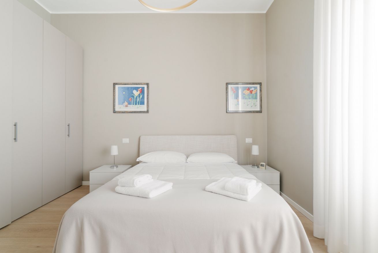 A hotel room with a large bed, two bedside tables, and two framed pictures on the wall.