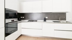 A modern kitchen with white cabinetry, a built-in oven, a stove, and a sink. - GuestHost - Bright apartment of about 85 sqm, able to accommodate up to 5 people, located on the mezzanine floor of a building (NO elevator - there are some steps to climb).The property is located in a residential area of ​​Milan, full of services an (Milan)