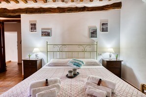 Makuuhuone, jossa on sänky, kaksi yöpöytää, sängynpääty ja seinä, jossa on kehystettyjä kuvia.