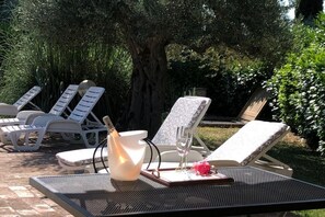 Poltronas de descanso ao ar livre, uma mesa e uma vela em um jardim.