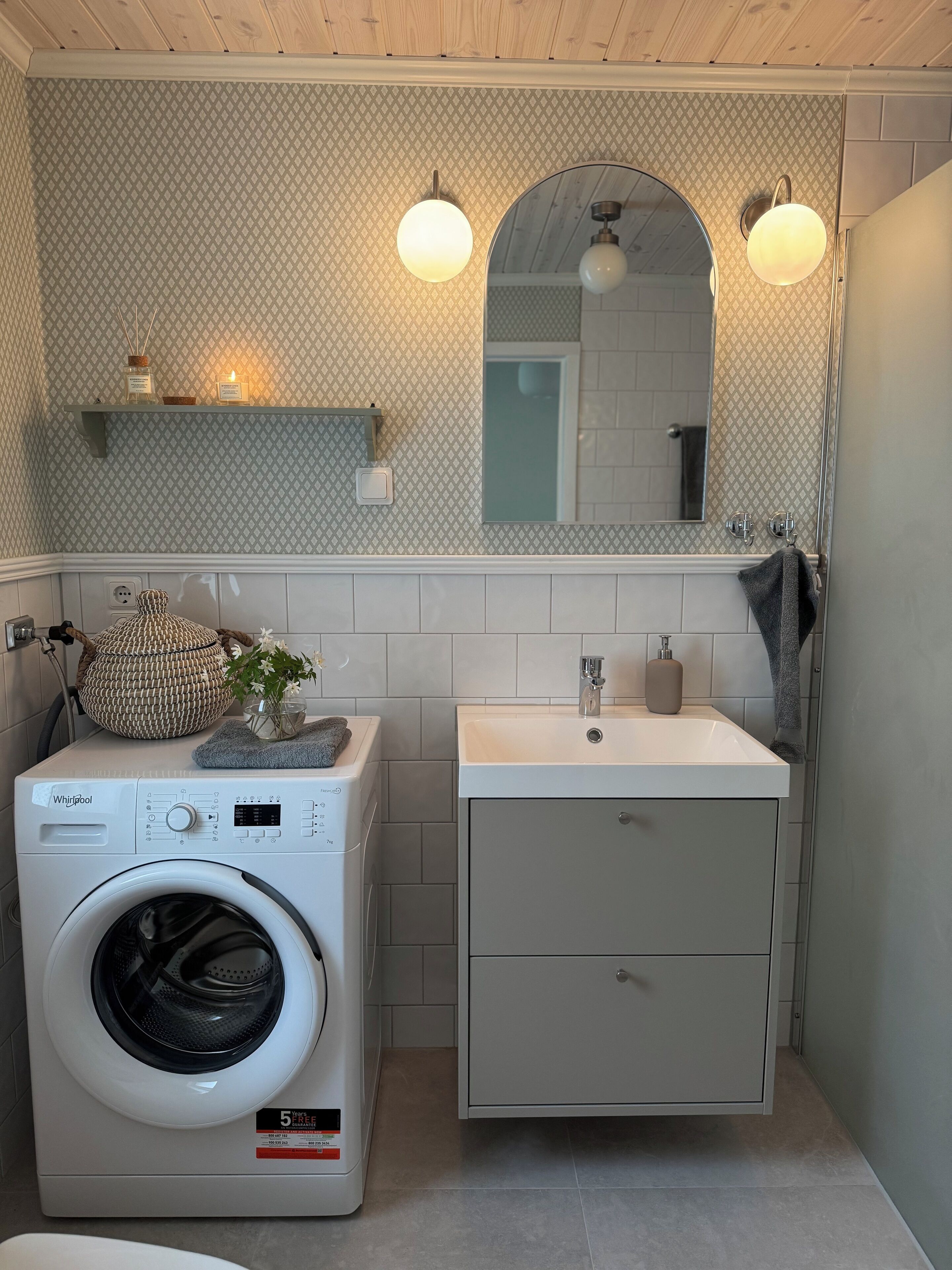 Un baño pequeño con lavadora, lavamanos y espejo.