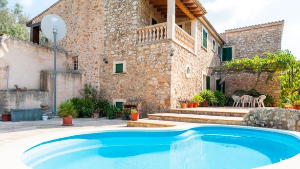 A stone building with a swimming pool, outdoor furniture, and potted plants. - Ses Roques in Santa Maria del Cam (Santa Maria del Camí)